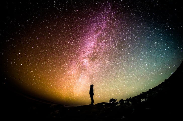 A man stands surrounded by the Milky Way